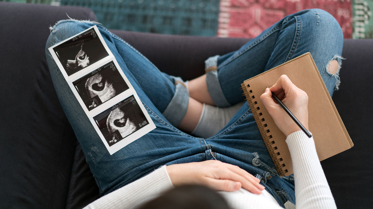 Woman in early pregnancy writing a health plan