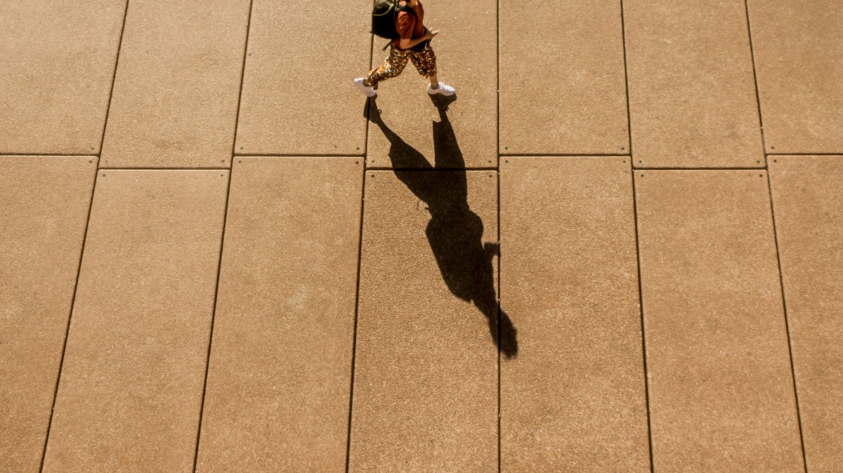 Long shadow of a young person walking