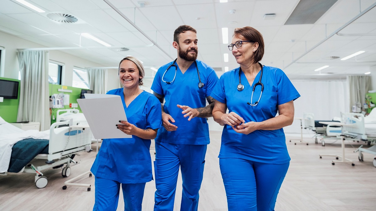 Three healthcare workers walking together in a hospital ward