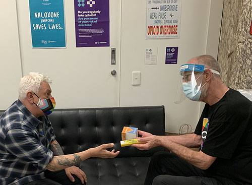 One man gives another two doses of naloxone